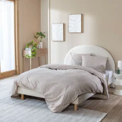 Lit tissu beige avec tête de lit bouclette